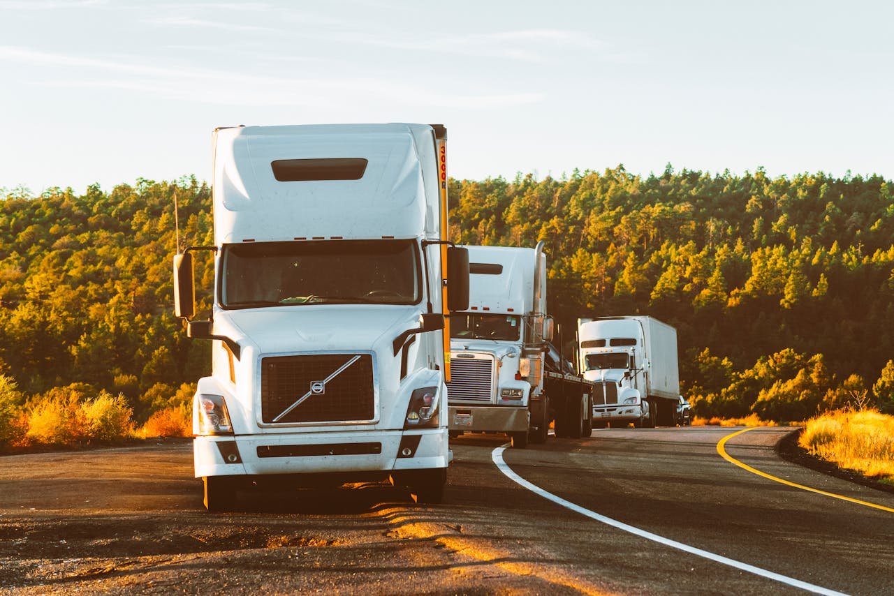 Inicio Three semi trucks driving on a highway through a forested landscape in Arizona.