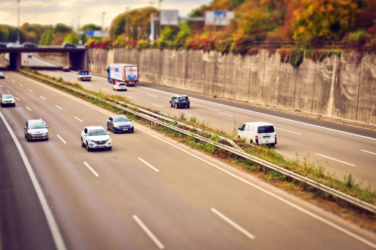Inicio Cars and trucks moving on a highway under sunny skies, showcasing road travel.