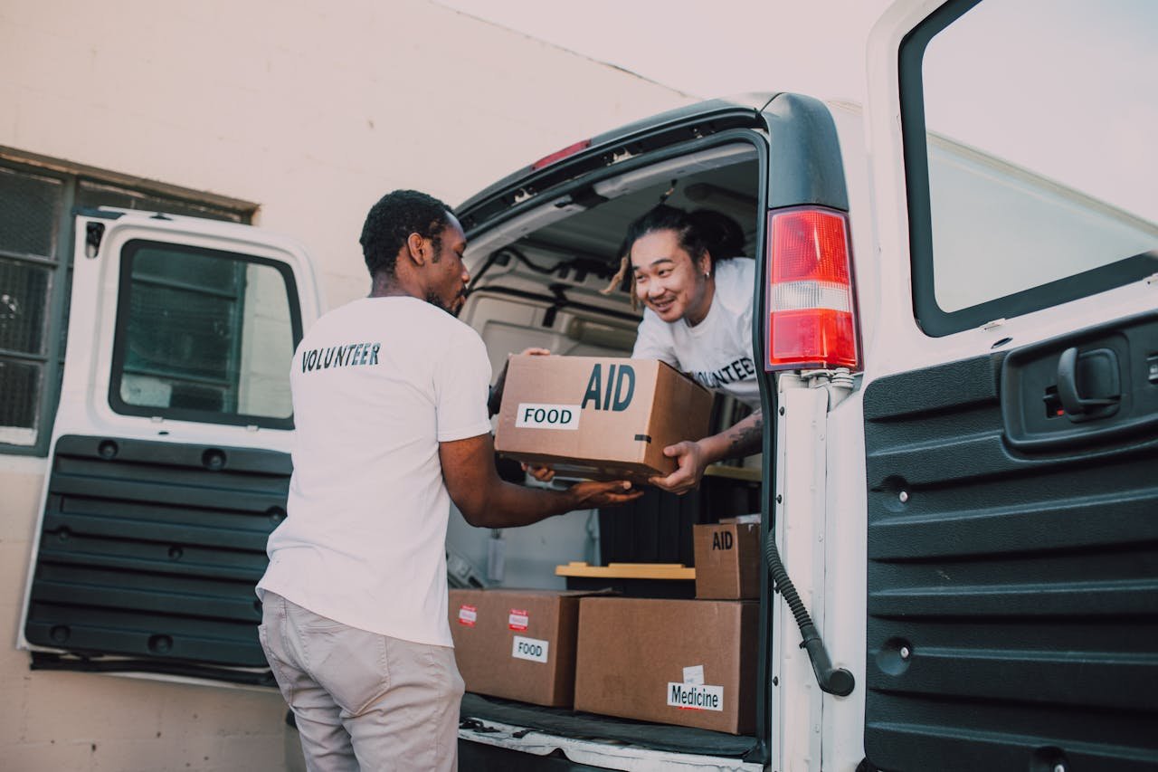 Servicios Volunteers unloading boxes of food and medicine from a van for community aid effort.